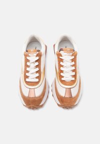 Ζεύγος καφέ, λευκών και μπεζ αθλητικών παπουτσιών με λευκά κορδόνια, πάνελ από δίχτυ και σουέτ, και κείμενο στη γλώσσα που γράφει "21 Rue St-Guillaume Paris".