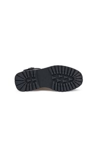 Czarna gumowa podeszwa buta z głębokim wzorem bieżnika, posiadająca zaokrąglone krawędzie i mały pasek wokół kostki zapewniający pewne dopasowanie. Gładka tekstura powierzchni.