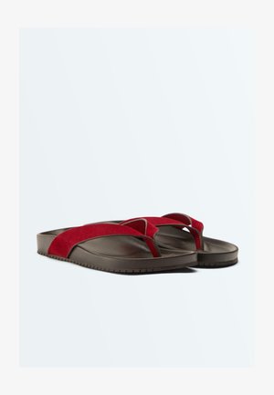 Brune klipklappere med brede røde ruskindremme og tåsplittet stil på en ensartet hvid baggrund.