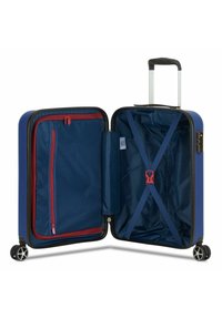 Maleta rígida azul con un exterior suave, interior espacioso, bolsillo con cremallera roja, correas cruzadas para un embalaje seguro y cuatro ruedas.