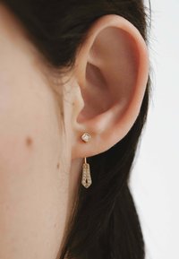 Pendientes de oro con un stud cuadrado que tiene una piedra clara y un diseño colgante con una forma texturizada y cónica adornada con pequeñas gemas transparentes.