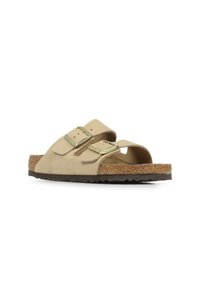 Sandali in suede beige con due cinturini regolabili, fibbie color oro e una soletta in sughero. Suola in gomma texturizzata per una buona aderenza.