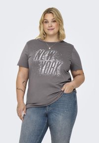 Šedé tričko s krátkým rukávem se bílým grafickým potiskem "NEW YORK". Uvolněný střih, v kombinaci s modrými denimovými džíny.