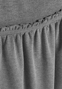 Țesătură gri cu textură moale, cu un accent cu volănașe de-a lungul taliei. Designul include material adunat pentru un plus de detaliu.