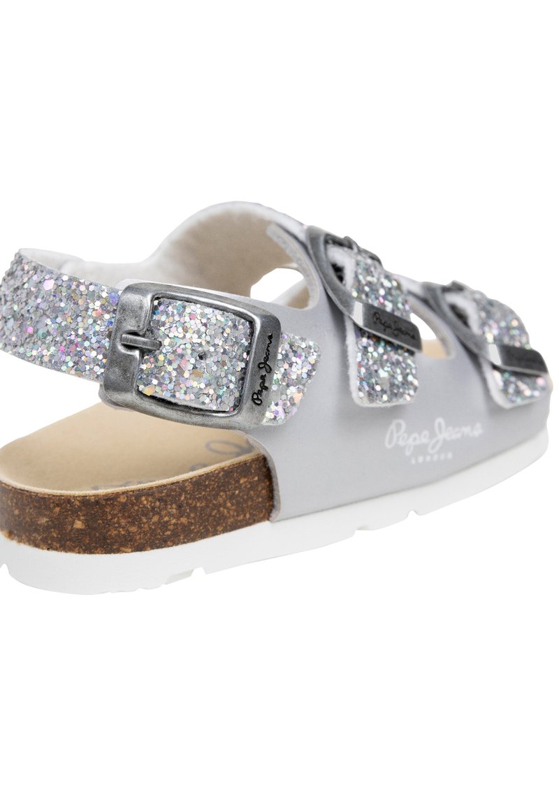 Sandalia de purpurina plateada con hebillas ajustables, plantilla de corcho y suela blanca, diseñada para uso casual.