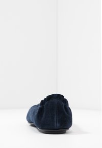 Ballerine en daim bleu marine avec un bout arrondi, dotée d'un dos texturé, de légers volants et d'une semelle en caoutchouc plate.