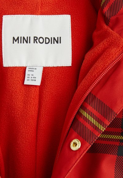 Chaqueta de forro polar roja con forro a cuadros y acentos en negro y amarillo. La etiqueta dice "MINI RODINI", incluye información de tamaño y cuidado.