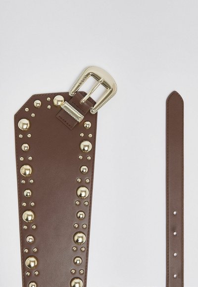 Ceinture en cuir marron avec une grande boucle dorée et des clous ronds dorés disposés en deux rangées parallèles à l'extrémité large.