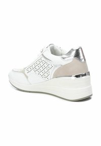 Sneaker bianca con dettagli perforati, accenti grigio chiaro, un tallone in metallo argento e una suola bianca spessa con un motivo testurizzato.