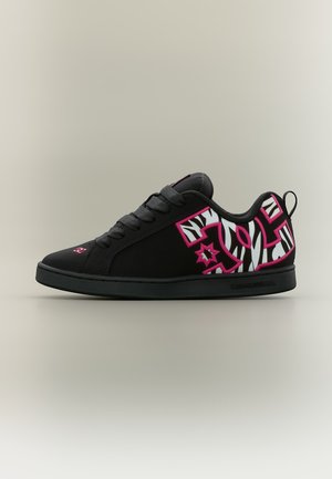 Baskets basses noires avec des lacets noirs, featuring un motif rayé zèbre blanc avec un contour rose sur le côté et une semelle en caoutchouc noire.