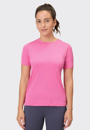 Short-sleeve pink athletic shirt made of smooth, lightweight fabric with a crew neck and seamless design, worn with navy leggings.