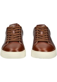 Zapatillas deportivas de cuero marrón con puntera redonda, suela plana de goma blanca y cordones marrones. Logotipo de GANT grabado en la lengüeta. Diseño clásico.