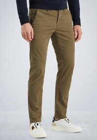 Khaki bukser med slim fit, lavet af bomuld. Har skrå lommer, bæltestropper og en glat overflade. Bæres med hvide sneakers.