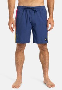 Shorts de baie bleumarin cu un cordon de ajustare în talie, având panouri laterale colorate în roz, portocaliu și galben, și un mic patch logo negru.