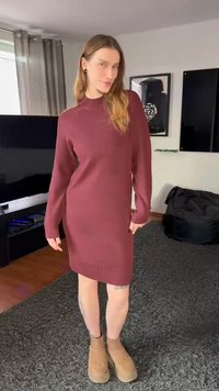 Obleka iz bordo pletenine z visokim ovratnikom in rebrasto teksturo, z dolgimi rokavi in sproščenim krojem, kombinirana s čevlji do gležnja v barvi konjaka.