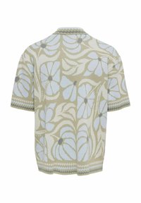 Chemise en maille à manches courtes avec des motifs floraux et feuillus bleu pâle sur un fond beige, avec une bordure zigzag aux manches et à l'ourlet.