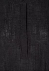 Černá lněná tkanina s texturovaným mřížkovým vzorem, se středovým zapínáním na knoflík a jemným leskem, který zvyšuje její vizuální hloubku.