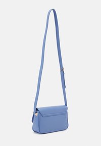 Blå crossover-väska i slätt läder. Har en platt, rektangulär design med ett viklock och en lång justerbar rem.