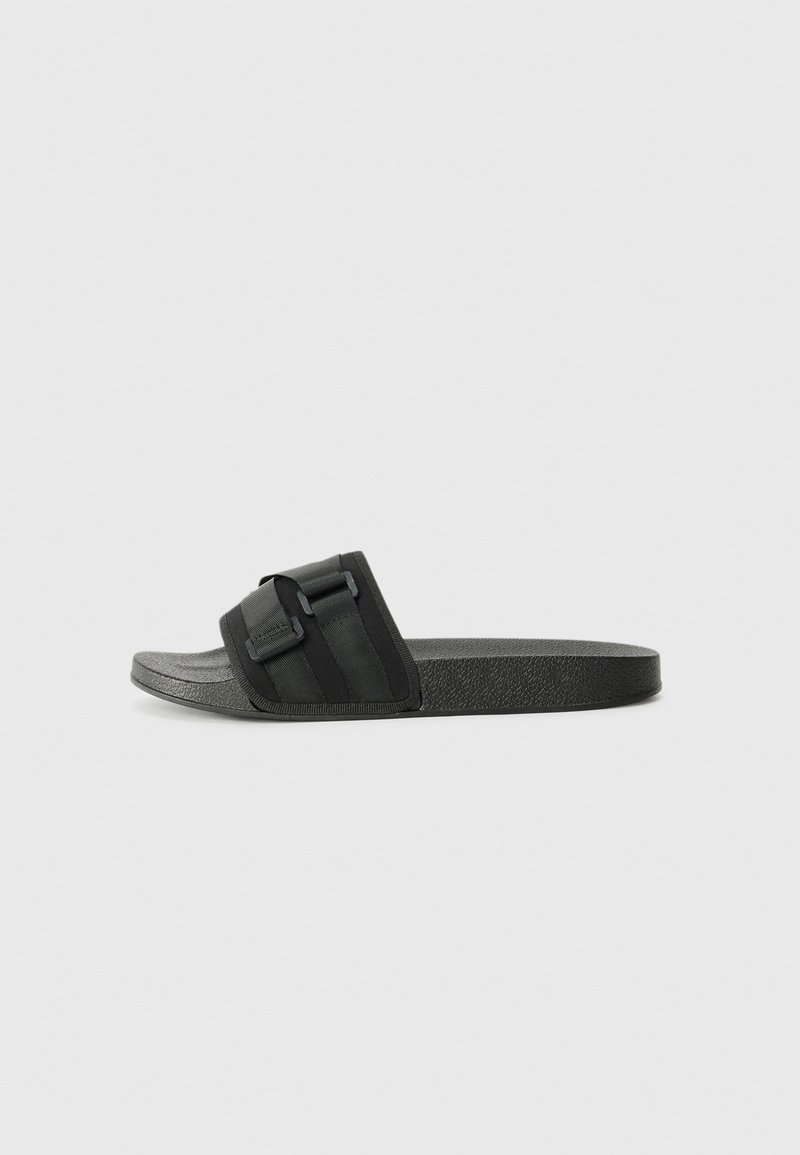 Black slide sandal featuring a textured sole, adjustable strap with buckle accent, and smooth footbed for comfort.