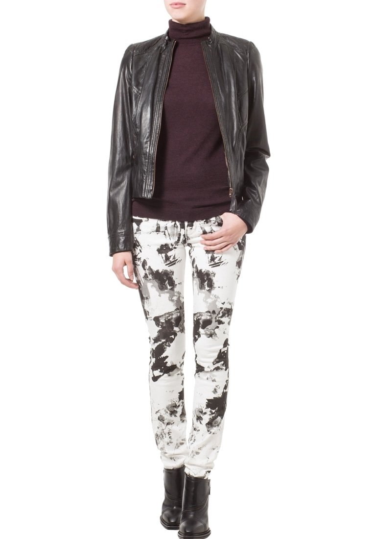 Černá kožená bunda, přiléhavý bordový rolák a bílé skinny džíny s černým abstraktním vzorem. Černé kotníkové boty dokončují tento outfit.