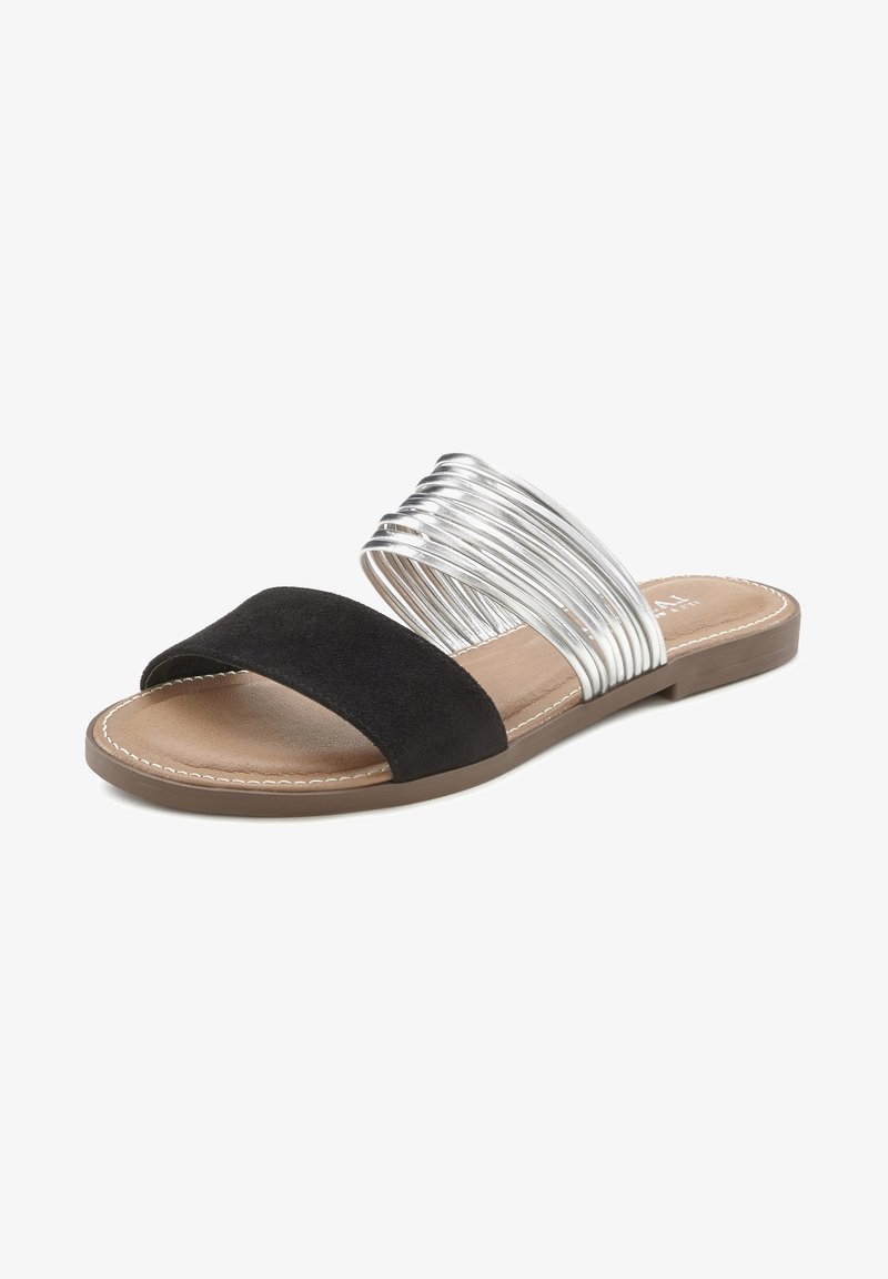Zwarte suède slipper met een brede band en een zilvermetallic spiraalaccent. Voorzien van een gevoerde inlegzool en een platte, bruine buitenzool.