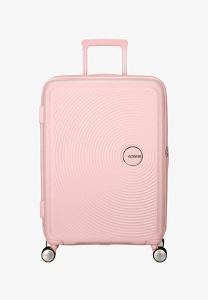 Valigia rigida rosa con design a costine, manico telescopico, quattro ruote e un dettaglio con logo rotondo. Texture liscia e leggero.