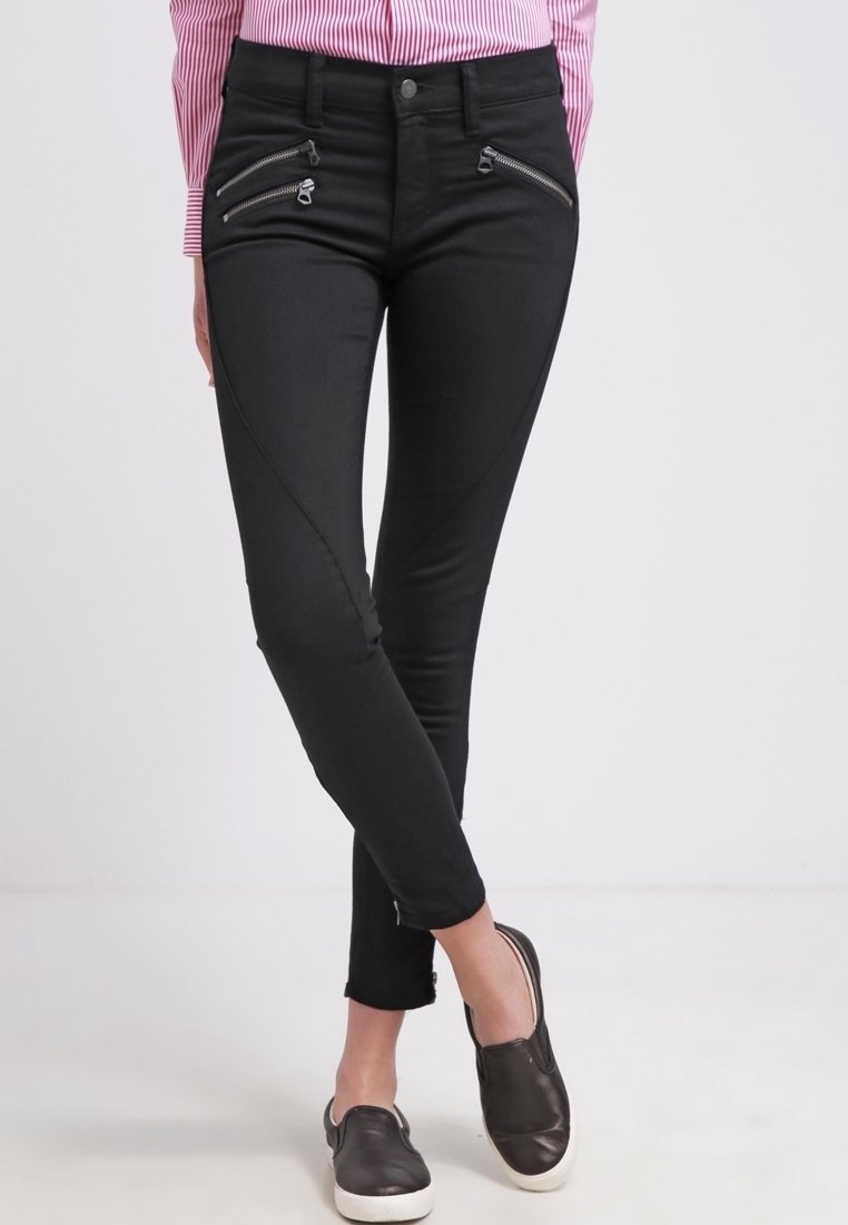 Černé skinny džínsy s ostrým švem, předními zipovými kapsami a mírným odhalením kotníků. Vyrobeny z elastického materiálu pro pohodlí.