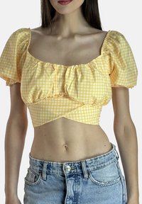 Gul gingham crop-top med pufærmer og firkantet udskæring, med rynkede detaljer og en tætsiddende talje, stylet med højtaljede denimshorts.