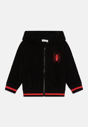 Felpa nera con zip realizzata in materiale morbido, con un logo di ragno rosso sul petto e dettagli a righe rosse sui polsini e sull'orlo.