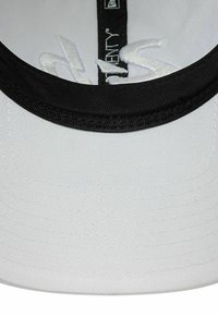 Weiße Kappe mit schwarzem Schirm. Verfügt über eine strukturierte Oberfläche und eine gestickte Verzierung auf der Vorderseite. Das Innenfutter enthält ein Markenetikett.