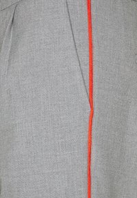 Grått tyg med subtil textur, med en ljus orange söm som löper vertikalt längs en sida.