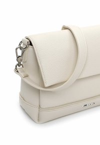 Krēmkrāsas ādas rokas soma ar teksturētu virsmu, strukturētu formu, platu pārklājamo vāku un noņemamu sudraba ķēdes siksnu.