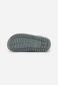 Sola de sapato de borracha cinza com um padrão de textura, apresentando ranhuras e seções elevadas para tração. Pequenas manchas claras visíveis na superfície.