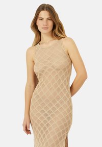 Nude mesh-mekko, jossa on timanttikuvio, olkaimeton muotoilu, pyöreä kaula-aukko ja sivuhalkio lisäyksinä. Kevyt neulottu materiaali.