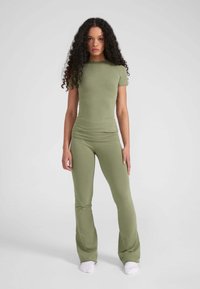 Olijfgroene aansluitende top en uitlopende broek van rekbare stof, met korte mouwen en een gladde textuur zonder zichtbare patronen.