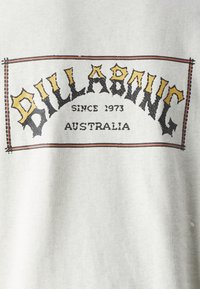 Γκρι φούτερ με εκτυπωμένο λογότυπο σε μαύρο και κίτρινο χρώμα. Ο σχεδιασμός περιλαμβάνει ένα περιφραγμένο ορθογώνιο σχήμα με το "BILLABONG" να εμφανίζεται με σαφήνεια.