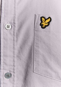 Camicia grigia con bottoni caratterizzata da un logo ad aquila nero e oro ricamato sulla tasca del petto, tessuto testurizzato e bottone con logo argentato.