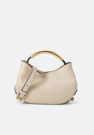 Beige leather handbag with a gold metal handle, a removable strap, and a soft, rounded design. Smooth texture with black accents.