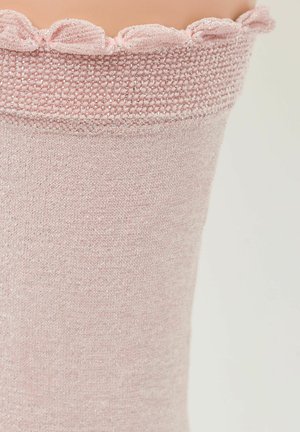 Helle rosa gestrickte Beinwärmer mit einer strukturierten Oberfläche. Schimmernde Fäden erzeugen einen subtilen Glanz. Der geraffte obere Rand verleiht eine dekorative Note.