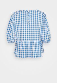 Blå og hvid gingham-bluse med puffede ærmer, flæsekant og knaplukning bagpå. Let bomuldsmateriale med glat tekstur.