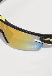 Czarne sportowe okulary przeciwsłoneczne w stylu wraparound, z lustrzanym pomarańczowym szkłem przechodzącym w niebieskie oraz fakturowanymi akcentami na ramce.