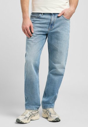 Ljusblå jeans i rak passform, med fem fickor och en urtvättad look, kombinerat med neutrala träningsskor.