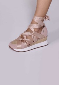 Zapatilla cuña con un upper de tela rosa, cintas de satén entrelazadas, textura tejida en la puntera y una suela de goma blanca.