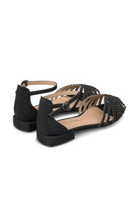 Sandalias planas negras con un acabado texturizado, que cuentan con múltiples tiras delgadas, un talón cerrado y una correa de tobillo con hebilla.