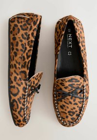 Scarpe flat con stampa leopardata realizzate in pelliccia sintetica testurizzata. Punta rotonda, lacci neri con dettaglio a fiocco e cuciture a contrasto lungo i lati.