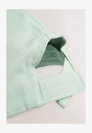 Lichtgroene stoffen baseballpet met klittenbandsluiting, close-up weergegeven tegen een neutrale achtergrond.