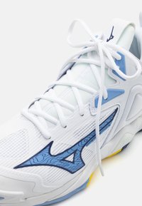 Zapatilla deportiva blanca con un upper texturizado, acentos azules y un distintivo logo en forma de ola. Presenta un cordón tradicional y una suela acolchada.