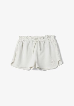 Short blanc à taille élastique avec panneaux en dentelle latéraux, lien à cordon, ourlets arrondis et petite broderie florale sur la jambe gauche.
