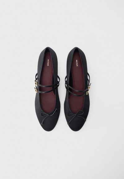 Čierne baletné baleríny s okrúhlou špičkou, jemnou textúrou, dvojitými prekríženými remienkami, zlatými akcentmi a detailom mašle vpredu. Viditeľné bordové stielky.