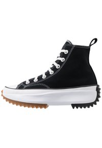 Czarne wysokie sneakersy wykonane z płótna, z białymi sznurówkami, gumowym okapem na palce i kolorowym, ząbkowanym bieżnikiem. Białe przeszycia jako akcent.
